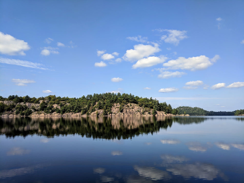 reflection of rocks and trees on lake