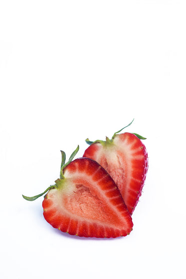 ripe strawberry cut in half on a white surface