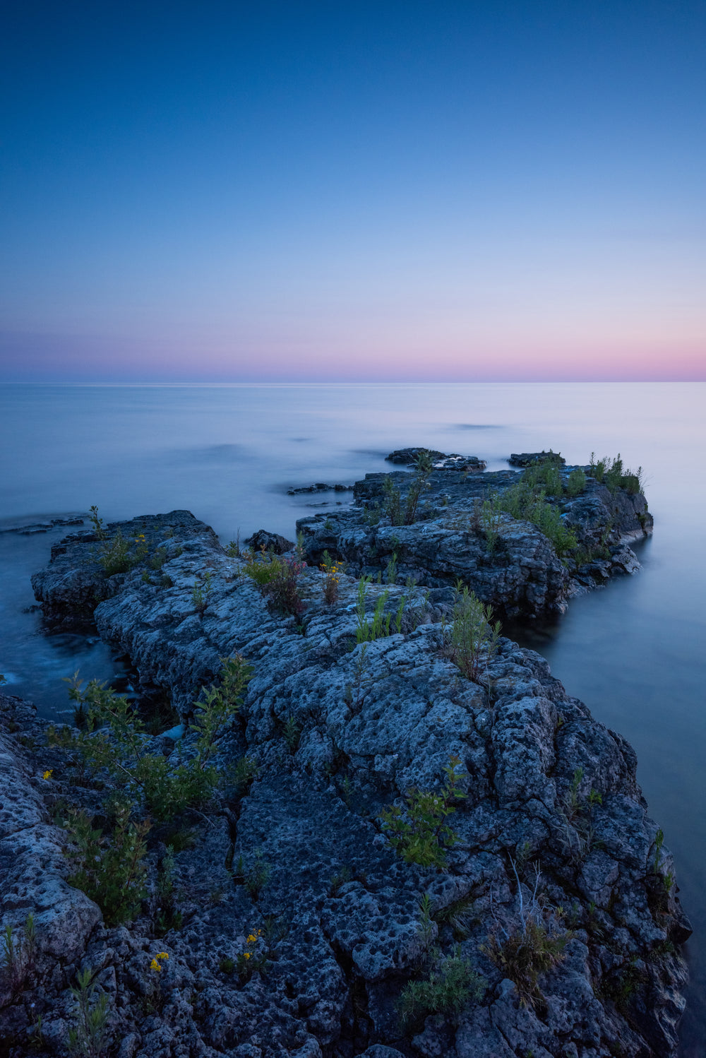 rock along shoreline leads out into calm waters