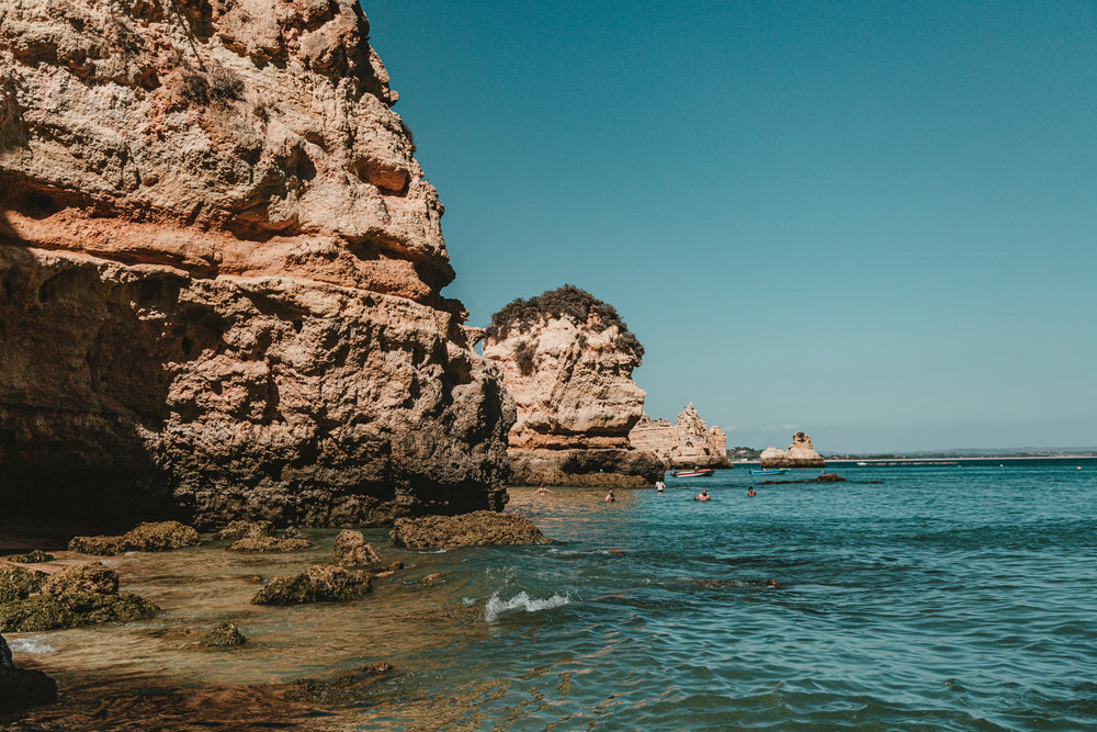 rocky cliffs of lagos distend into blue ocean waters