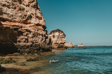 rocky cliffs of lagos distend into blue ocean waters