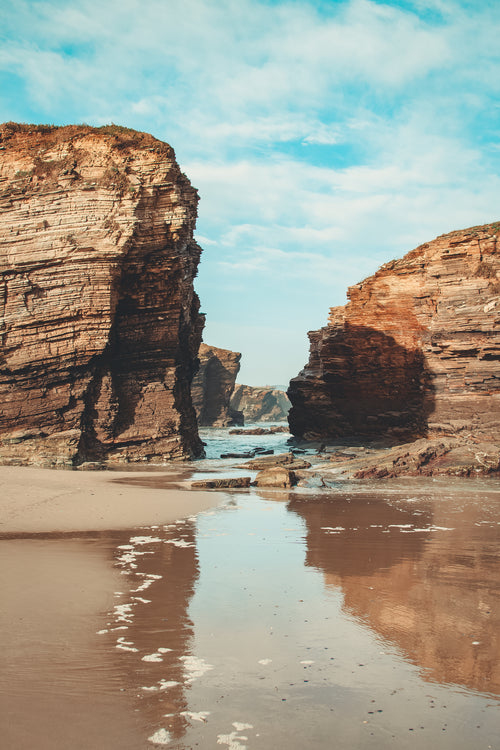 rocky cliffs stand over sandy beach