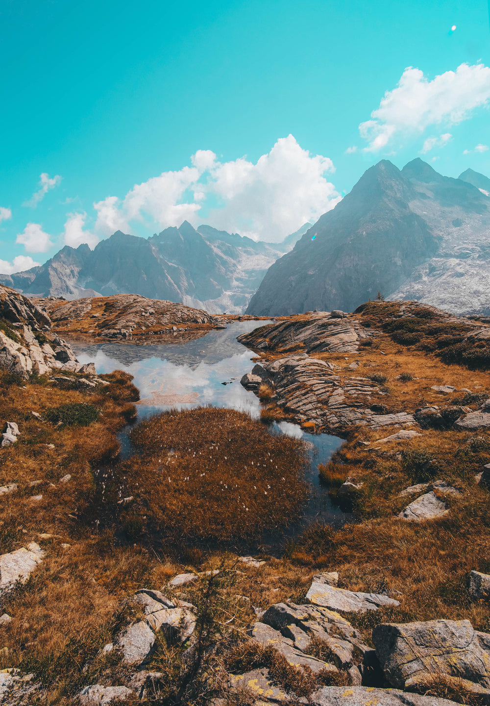 rocky hill top reflects mountains in a pool of water