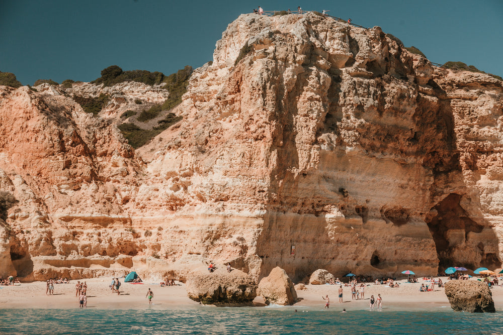 rocky limestone cliffs loom over a sandy beach