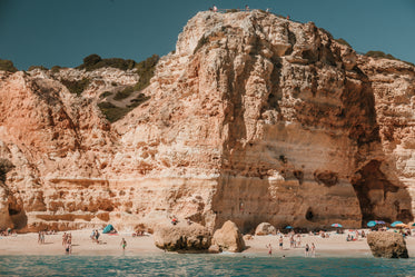 rocky limestone cliffs loom over a sandy beach