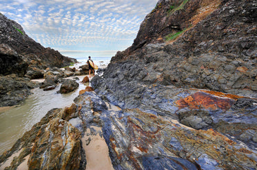 rocky shore line with a person holding a surfboard