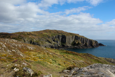 rolling green hills give way to sheer grey cliffs