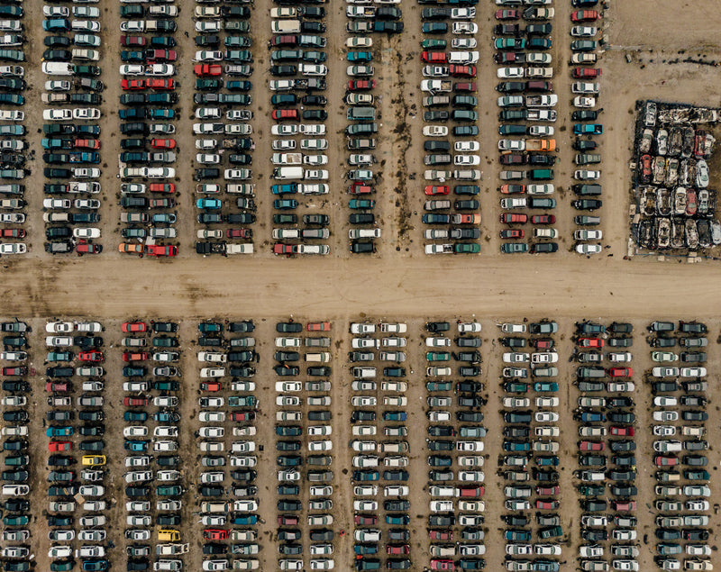 rows of cars in junk yard aerial - a parking lot full of cars