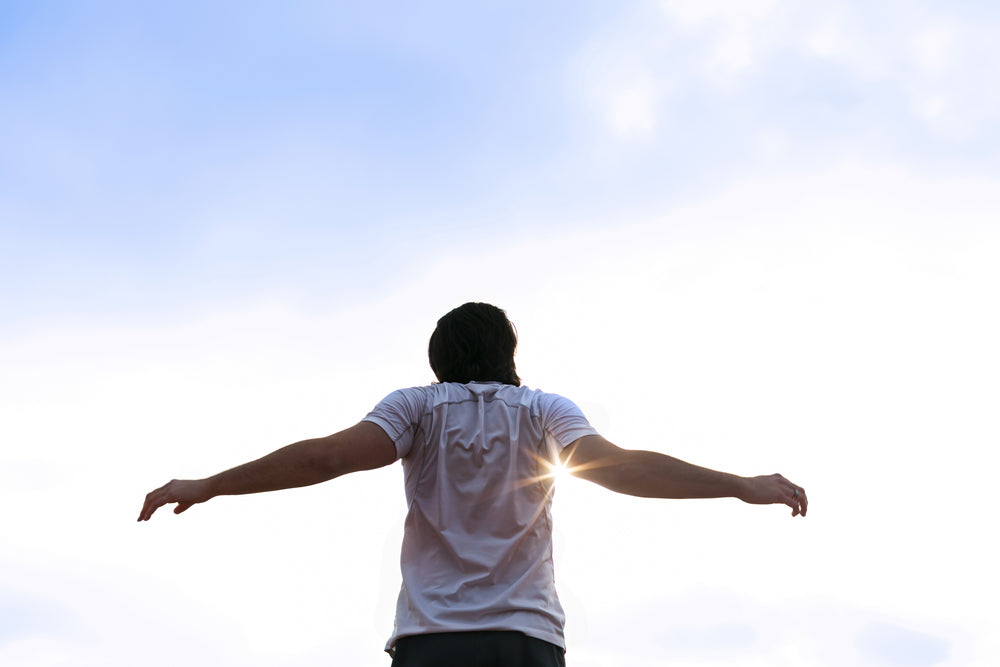 runner stretching arms in sun