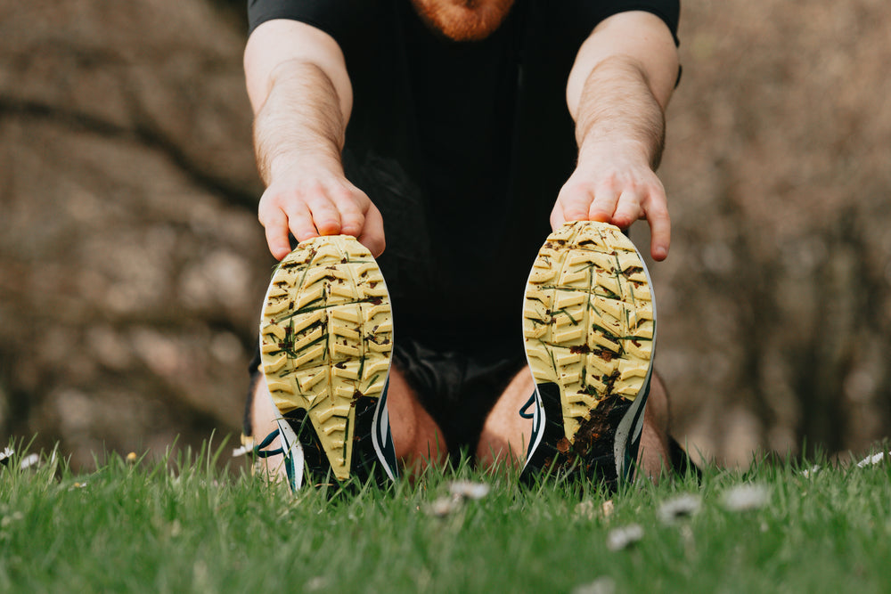 running shoes on green grass of a person stretching