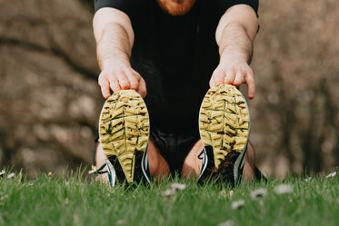 running shoes on green grass of a person stretching