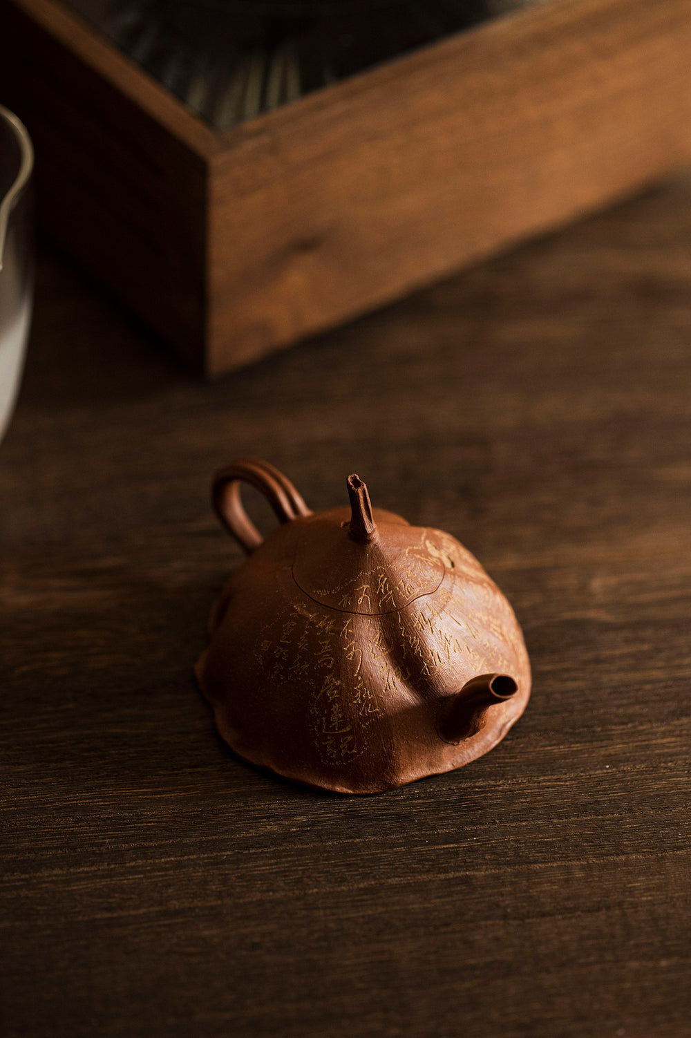 rust colored carved teapot sits on a wooden table