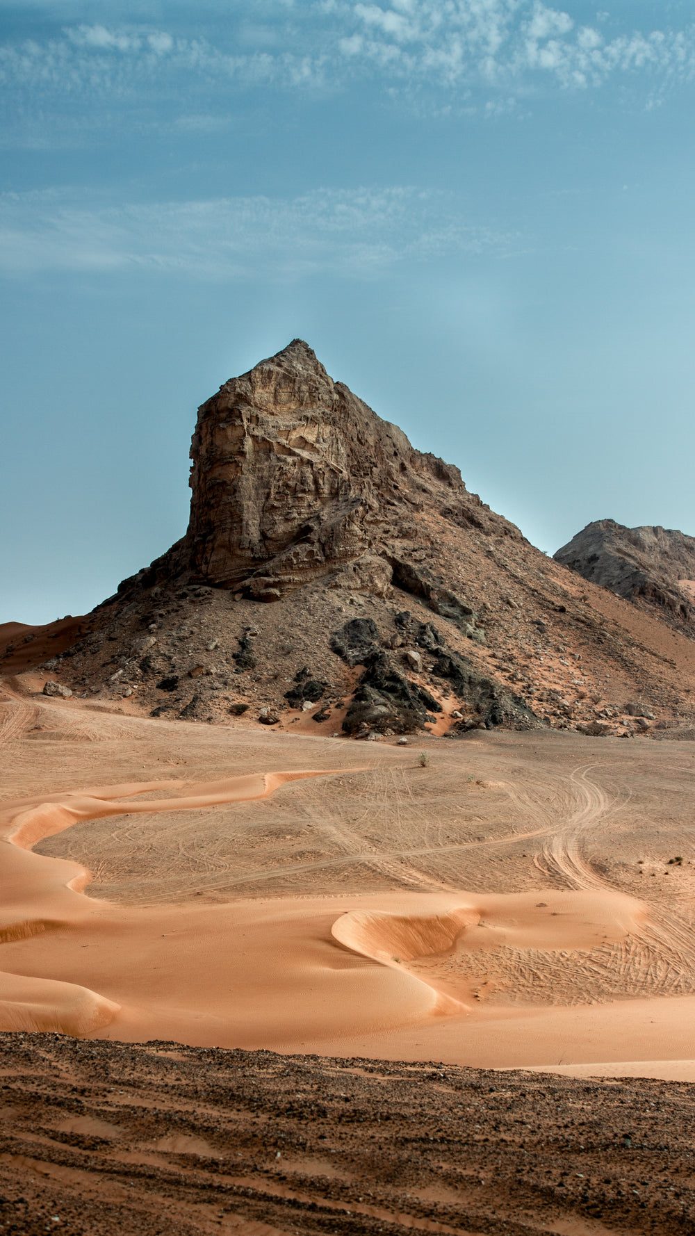 rust colored sand and a large rocky hill