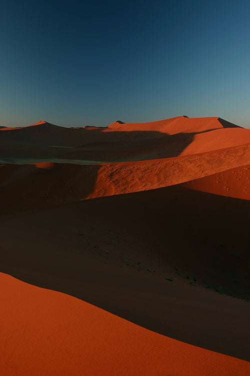rust colored sand dunes against a deep blue sky