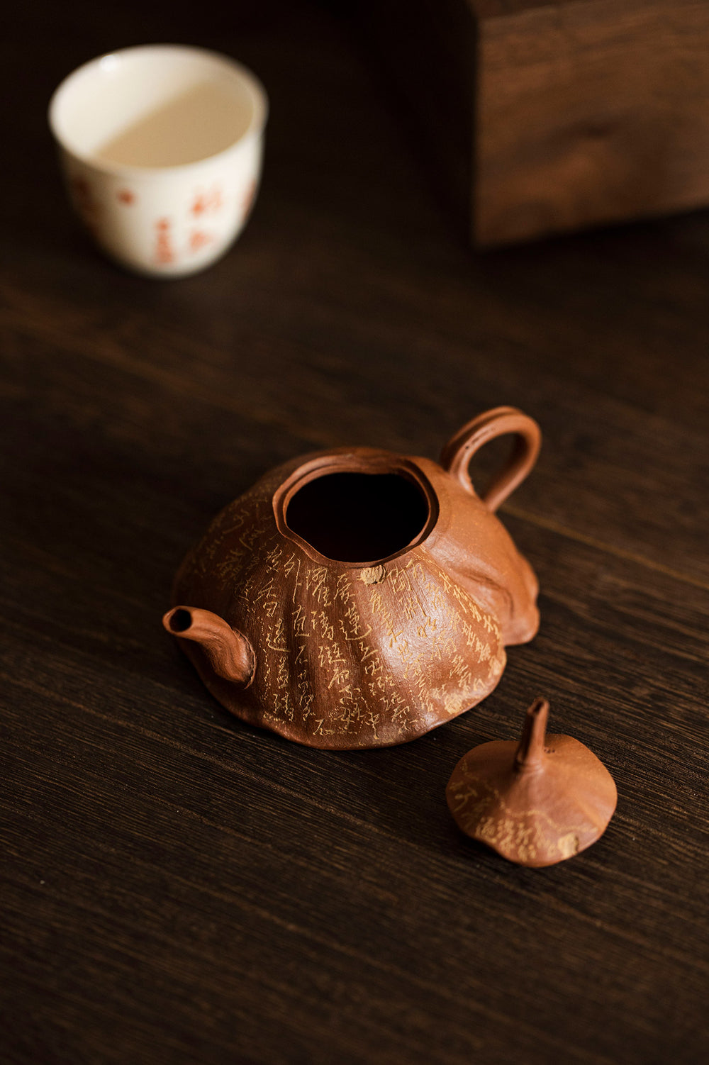 rust colored teapot with its lid of on a wooden table