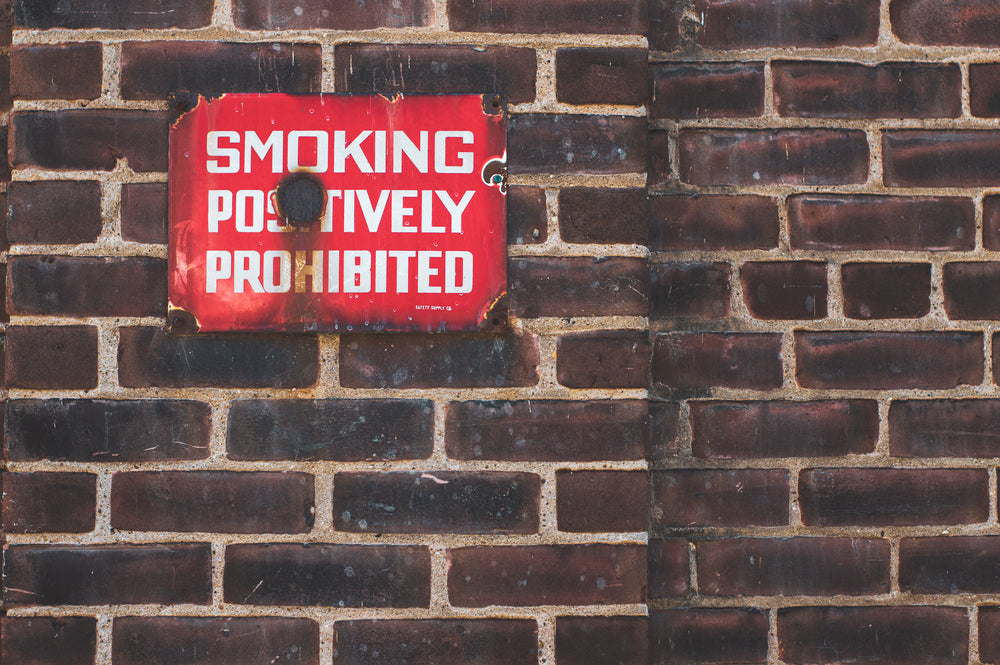 rusting no smoking sign on brick wall