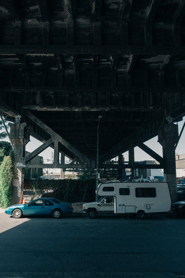 rv and car parked under iron bridge