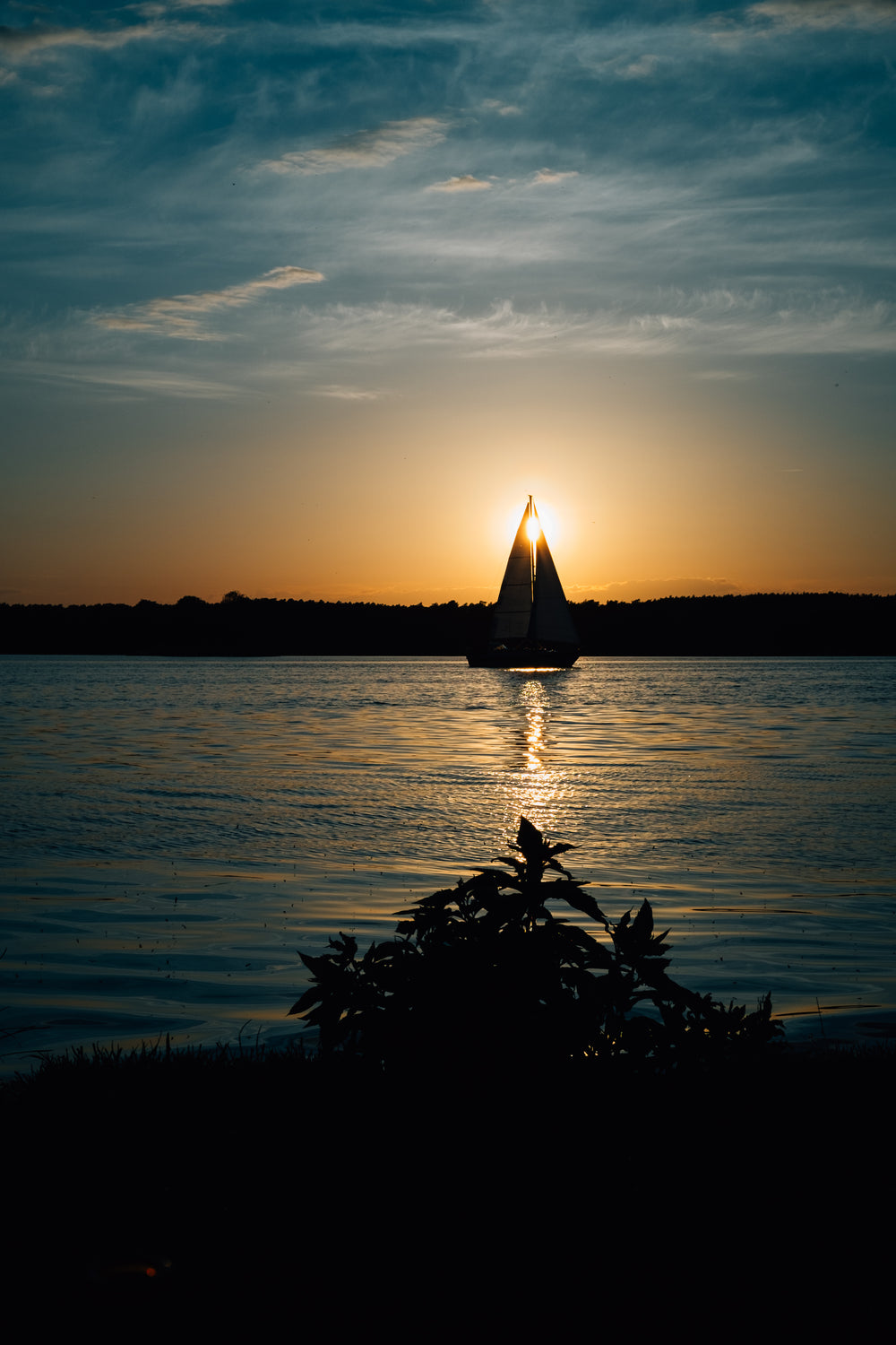 sail boat on quiet lake at sunset