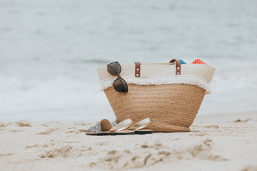 sandals and a beach bag on a white sandy beach