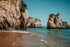 sandy beach by rocky cliffs