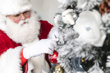 santa dresses the tree with an ornament