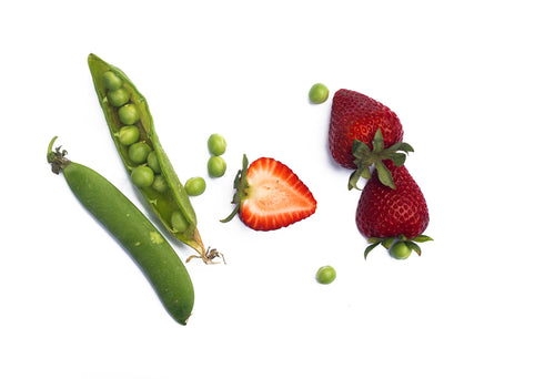scattered green peas in their pod with strawberries