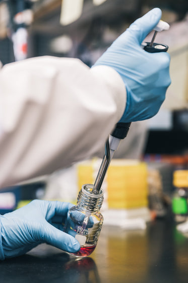 scientist injecting red liquid into bottle