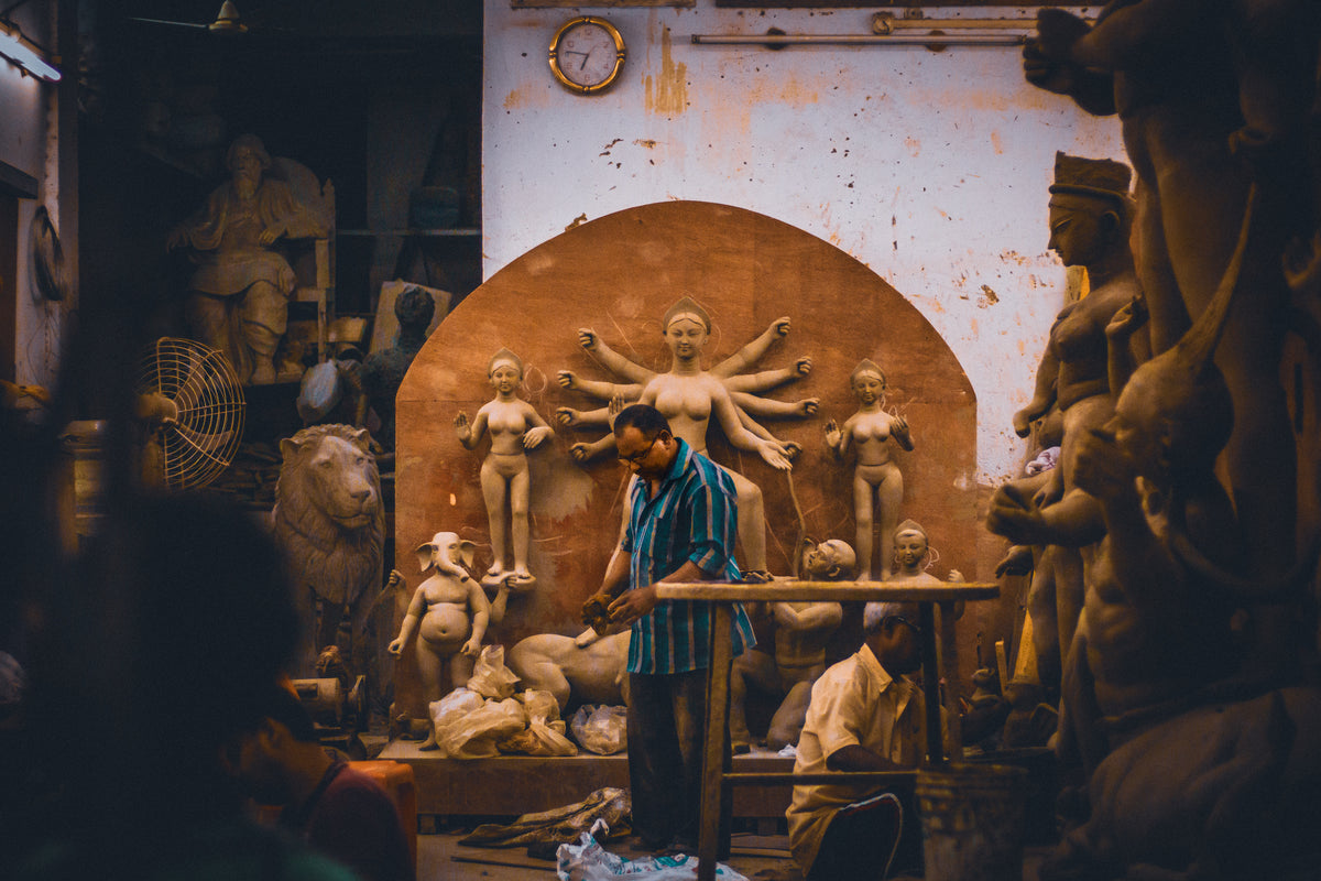 sculptors standing in studio working with clay
