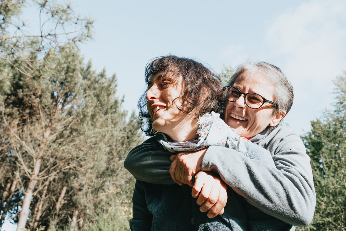 senior woman in glasses hugs a woman from behind