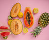several different fruits lay on a pink background