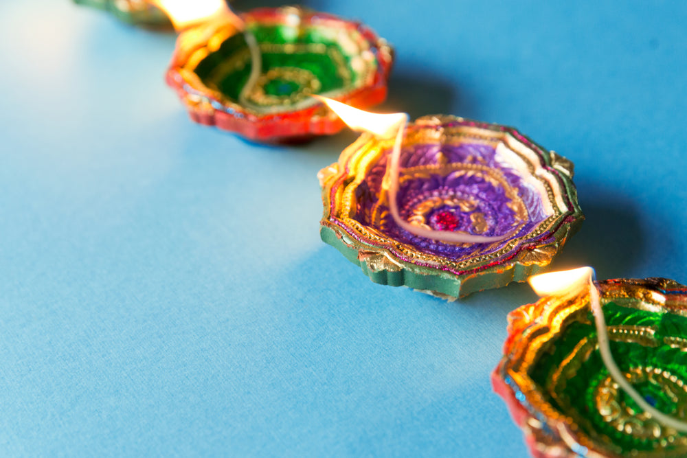 several diya lamps sit aflame a blue background