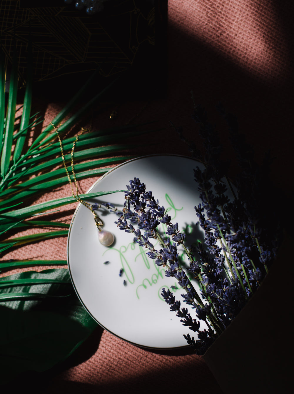 shadowed flatlay of lavender and a necklace
