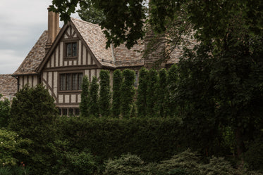 side of a brown house with tall hedges obscuring view