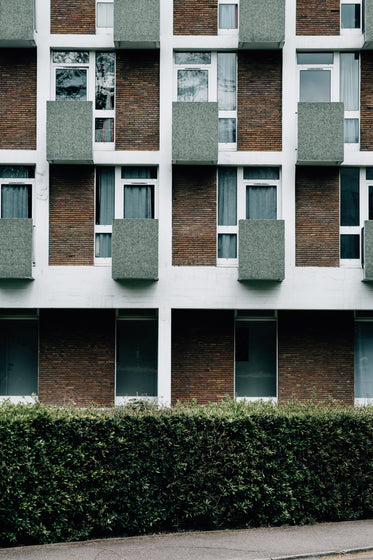 side of a building with a green hedge in front