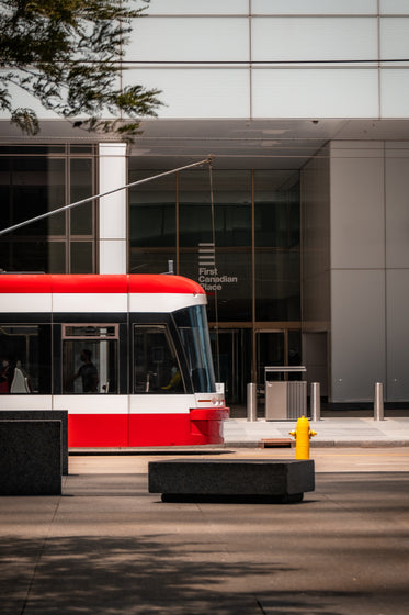 side of a glass building with a red streetcar