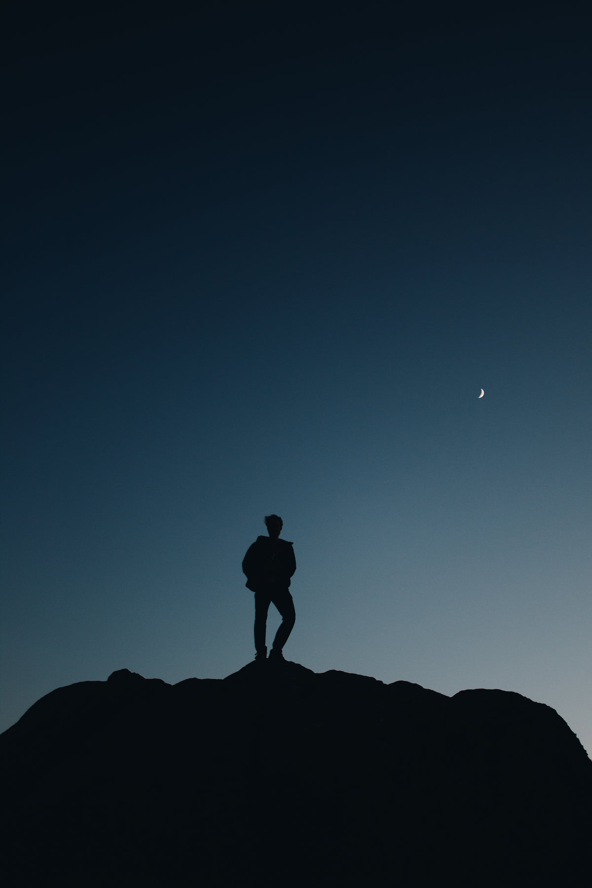 silhouette of a person below crescent moon