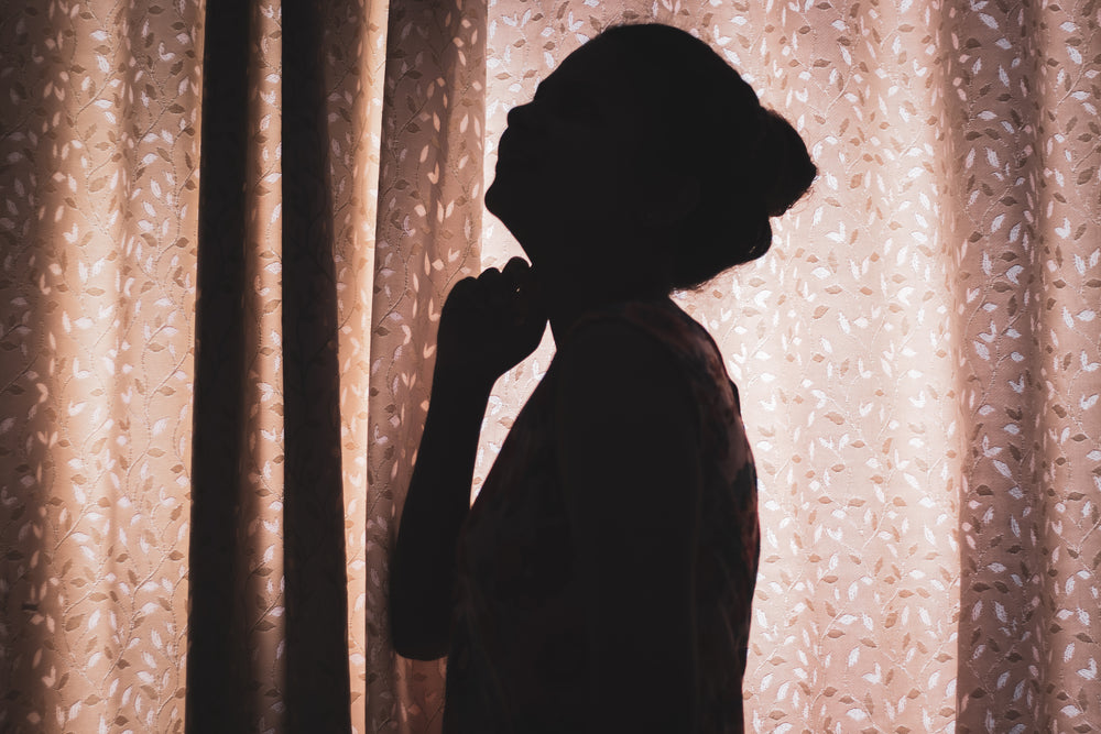 silhouette of a person in front of a closed curtain
