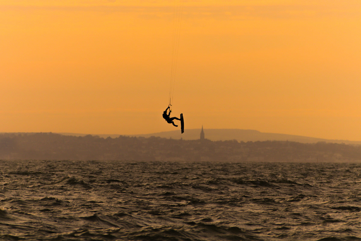 一个人的剪影风筝冲浪在波浪的水