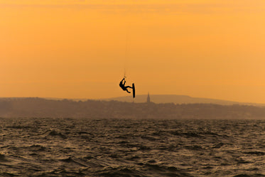 silhouette of a person kite surfing in wavy water