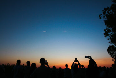 silhouetted people taking pictures of the sky