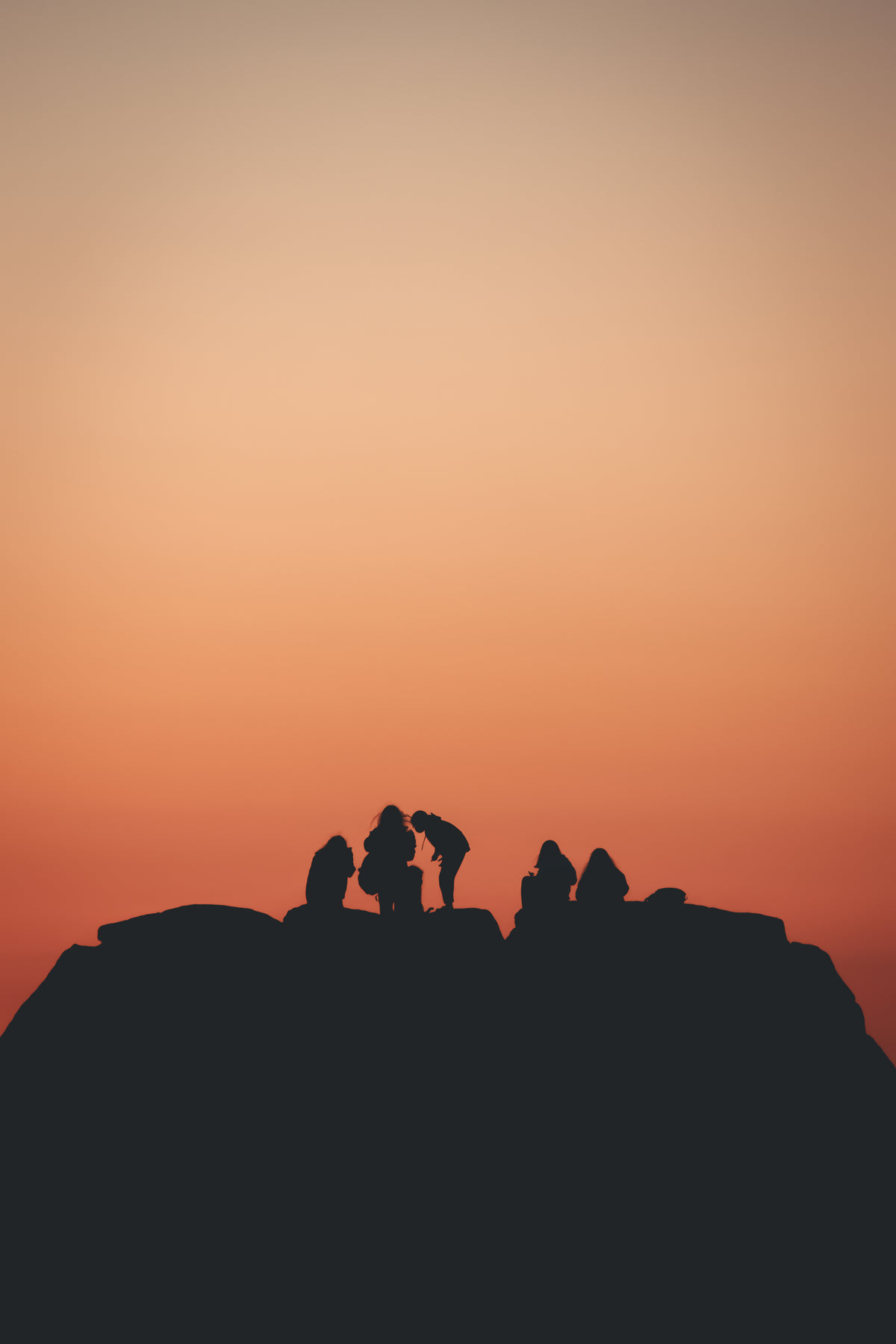 silhouetted people with a orange sky behind them