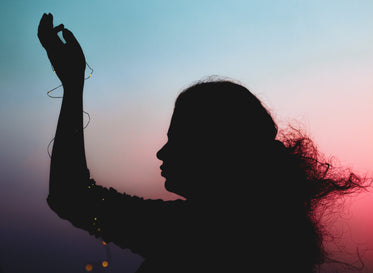 silhouetted person holding one hand in front