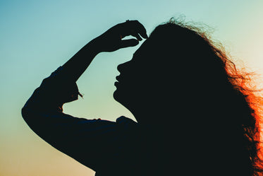 silhouetted person running hand through their hair