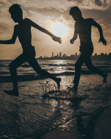 silhouettes of two people splashing on the beach