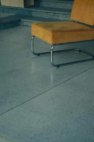 silver metal chair with yellow cushions on tiled floor