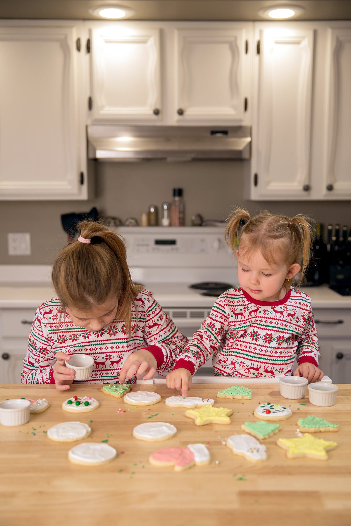 sisters decorating festive cookies