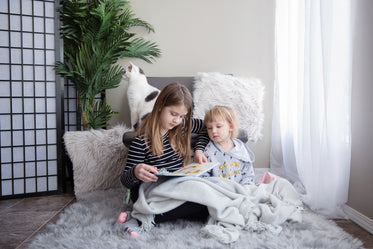 sisters sit together reading a book