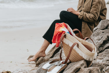 sitting behind a wicker beach bag on rockys by the beach