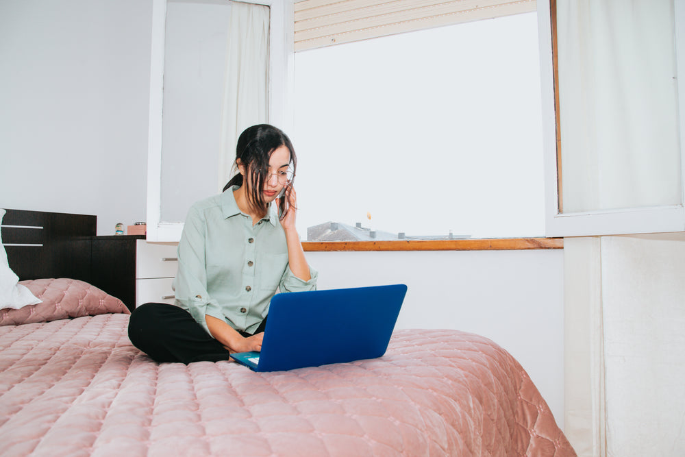 sitting crossed legged on a bed with a laptop in front