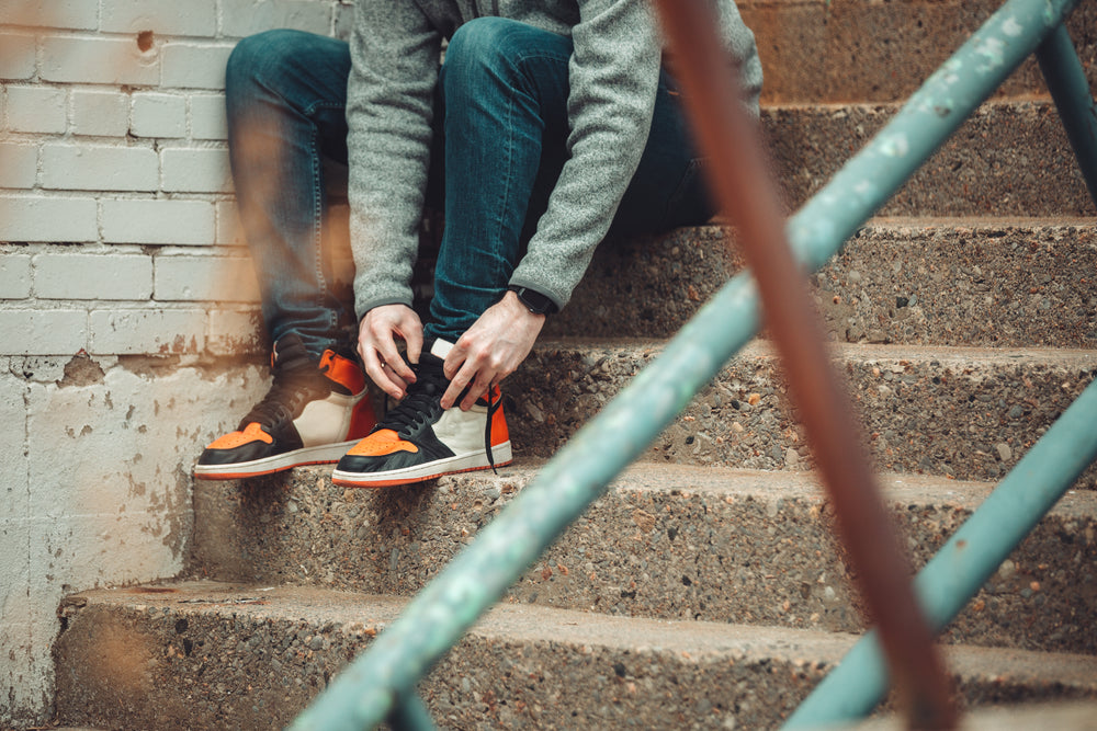 sitting for a moment to tie the laces of fashion sneakers